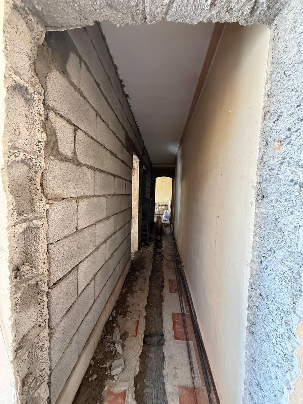 Pasillo antes de la reforma en Tinajo, con el tabique de bloques levantado, las rozas abiertas y el suelo original
